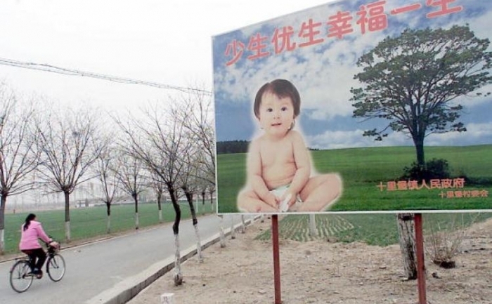 O femeie trece pe langa un panou care încurajeaza cuplurile de a avea un singur copil, într-o suburbie din Beijing, 25 martie 2001.