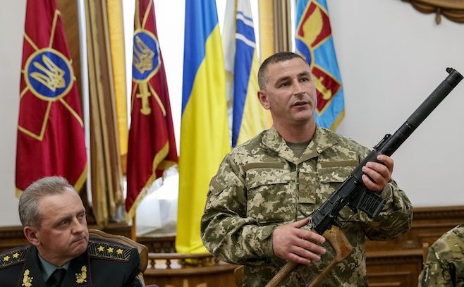 Un  comandant militar ucrainean prezintă, la o conferinţă de presă în 18   mai 2015, o armă găsită asupra unui soldat rus capturat în Ucraina. (Captură Foto)