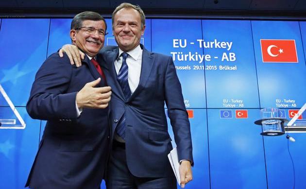 Premierul turc Ahmet Davutoglu (st) şi preşedintele Consiliului European Donald Tusk se felicită după finalizarea summitului UE-Turcia din Bruxelles, 29 noiembrie 2015.